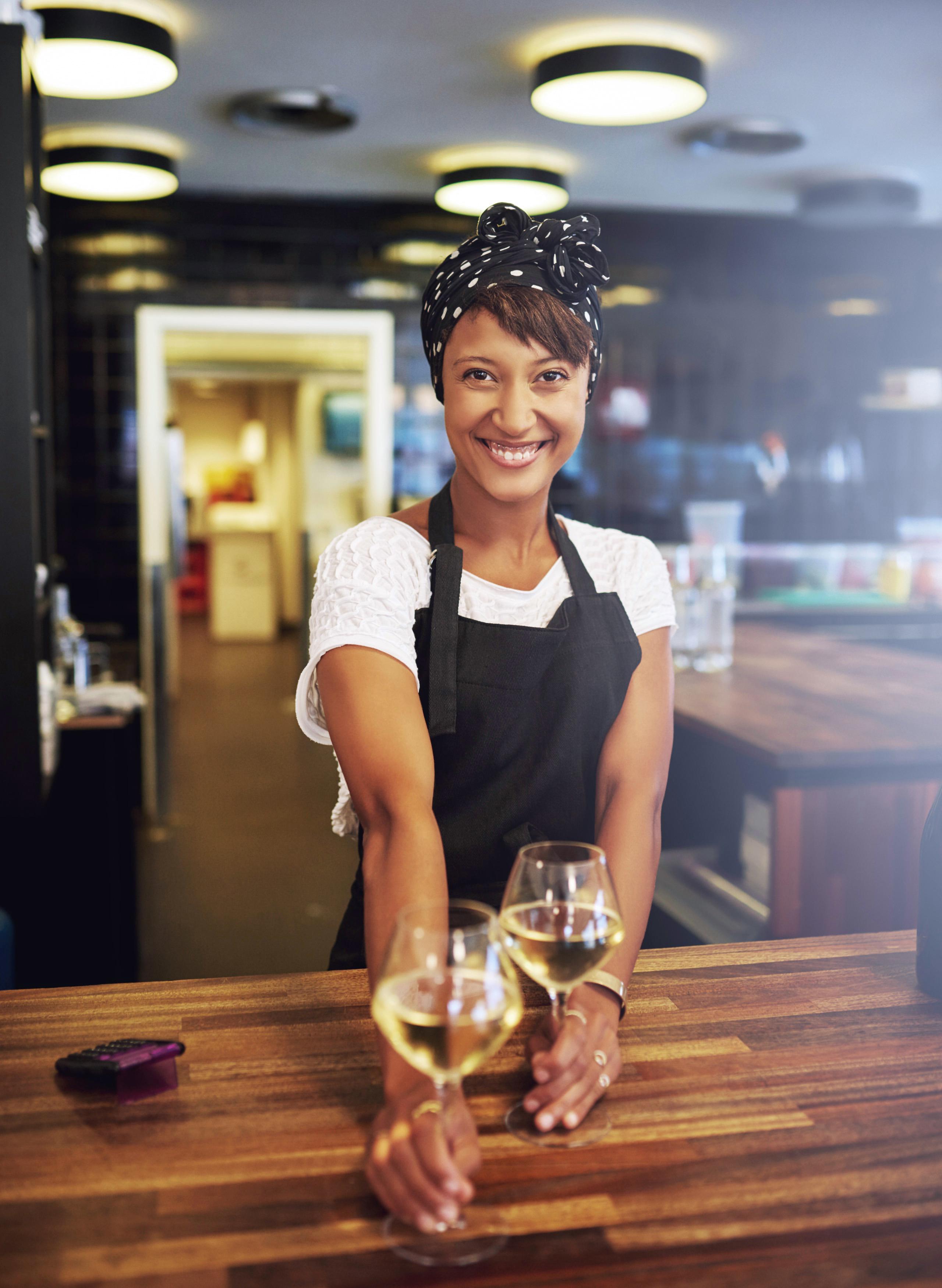 Small business owner holding a pair of wine glasses.
