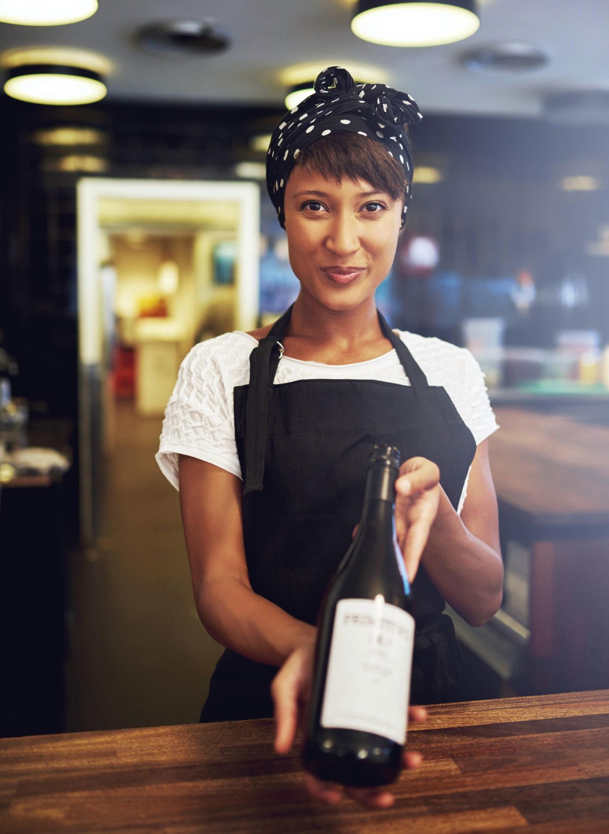 Small business owner holding a bottle of wine. 